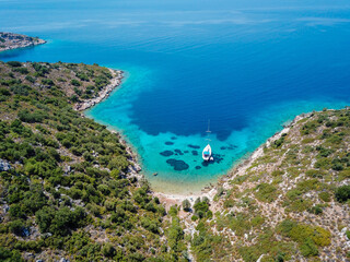 Sailing boat anchored in a beautiful turquoise color water bay in aegean sea.
