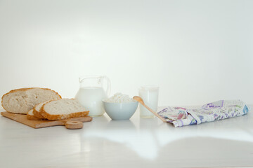 Milk in a glass jar, cottage cheese and  bread on the table. White background.