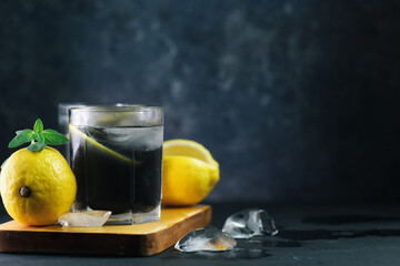 summer ice lemonade with lemon, mint and charcoal on a dark table copy space