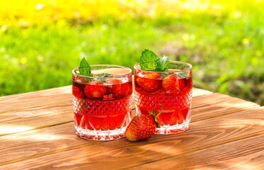 Strawberries on the table and a fresh drinks with mint on sunny day