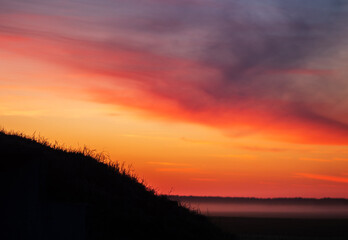 Colorful summer sunset over a misty field