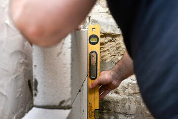 The worker checks the level of the wall of the foam block masonry, the use of the building level in the euro decoration and repair.