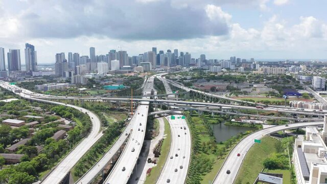 Aerial Miami cityscape panorama view with busy highway on the foreground. 4k drone view of cars on multi-level roads on sunny day. Beautiful background for transportation business, Miami Florida, USA