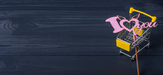 Shopping cart and love sign on a black wooden background