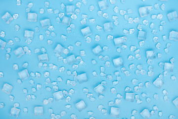 Ice with water drops on blue background. Scratched ice cubes and crumb.