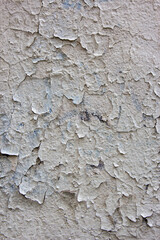 Cracked flaking white paint on old stone wall. Old Weathered Painted White Plastered Peeled Wall Background. Cracked Flaked Shabby Wall With Rundown Stucco Layer Texture.