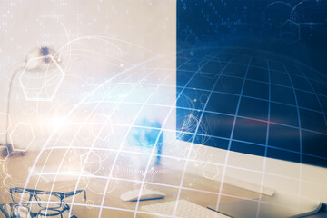 Double exposure of desktop with computer and world map hologram. International data network concept.