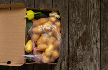 young potatoes in a bag and in a paper box with vegetables on the table bought at the bazaar close...