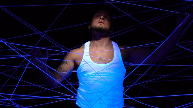 Video of man tangled in white threads in ultraviolet