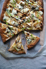 Homemade oval shaped pear & gorgonzola pizza on baking paper.