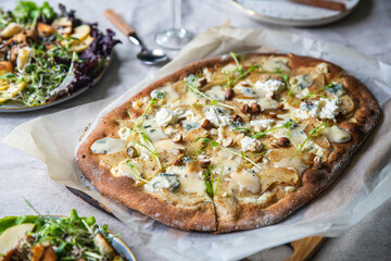 Table served with homemade oval shaped pear & gorgonzola pizza on baking paper and turkey and apple salad..