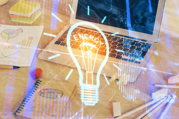 Computer on desktop in office with bulb icon hologram. Multi exposure. Concept of idea.