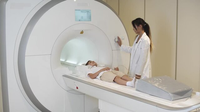 Magnetic resonance imaging, young woman doctor performs a magnetic tomographic examination of a boy, MRI, modern technologies in medicine.