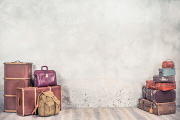 Vintage classic outdated trunks luggage, old antique leather suitcases, backpacks front concrete wall background. Travel baggage concept. Retro style filtered photo 