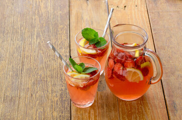 Summer pink lemonade with strawberries, mint and lemon on a rustic background