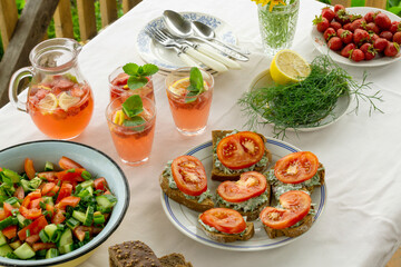 Dinner table with various snacks and summer strawberry lemonade outdoors