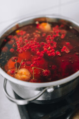 Fresh fruits are boiled in boiling water in a metal pan on the stove. Delicious stewed apricot, apples, cherries, raspberries. Photography, concept.