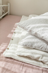 Pile of textile linen pillows, blankets, bedclothes. Natural organic cotton. Morning mood.