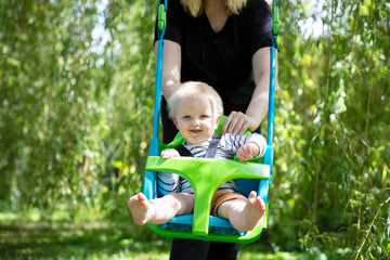 A little boy having fun playing on a swing under a tree in a garden