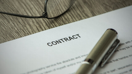 A contract on the desk. Pen and glasses on the desk.