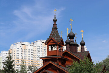 Fototapeta na wymiar Wooden orthodox temple on residential buildings background. Church of Saints Constantine and Elena equal to the apostles in Moscow