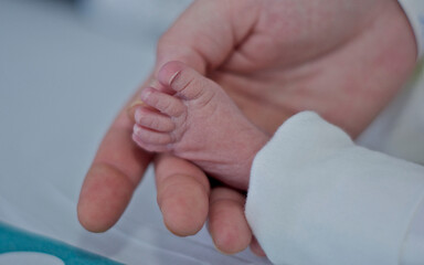 Foot of a newborn in the hospital holding his mother's hand