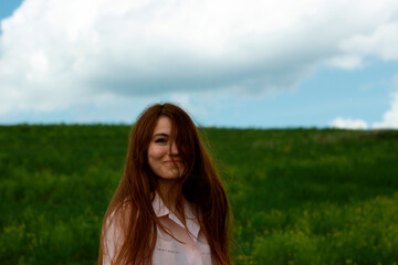 Happy girl with flying hair on the field. Portrait of a smiling girl against a green field.