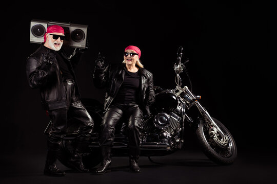 Photo of old bikers grey hair man lady couple moto chopper rock festival meeting listen tape recorder heavy metal music show horns wear rocker leather outfit isolated black color background