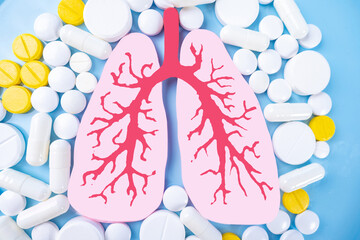 Lungs and tablets on a blue background. Medications for the treatment of lung diseases. Antibiotics...