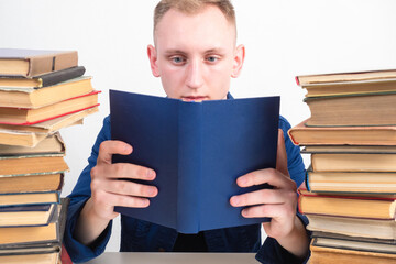 The man is reading a paper book enthusiastically. A person among the stacks of books. A lover of reading. Bibliophile. Hobby reading books.