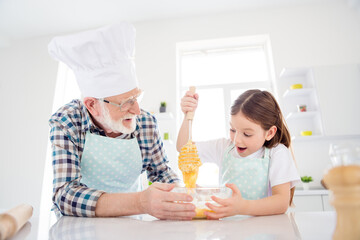 Close-up portrait of nice cheerful cheery glad grey-haired grandpa grandchild cooking domestic homemade tasty yummy dough cookies having fun leisure in modern light white interior kitchen house