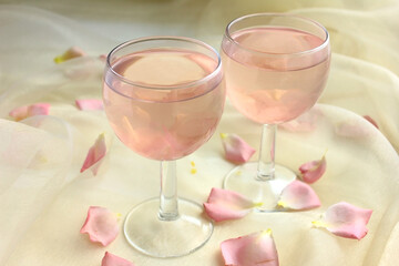 Two glasses with pink lemonade and rose petals. Romantic date, event.