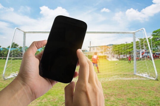 Hands use smartphones record soccer competition match in football stadium.
