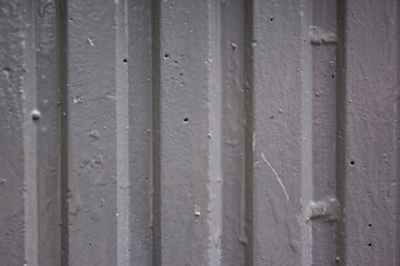 Corrugated sheet metal, badly painted with grey paint for background. Metal corrugated roofing sheet. Painting of metal surfaces for rust control. Abstract background for sites and layouts.