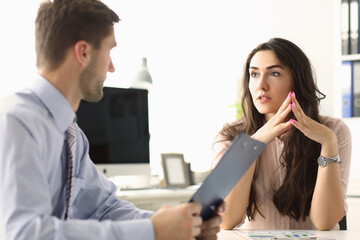 Two young employees discussing their work while sitting in the office. Teamwork and partnership concept