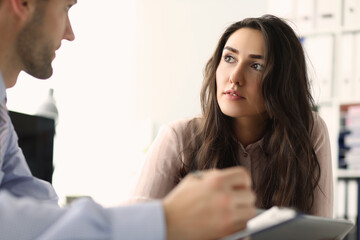 Two young employees looking at each other in the office while talking. Teamwork and partnership concept