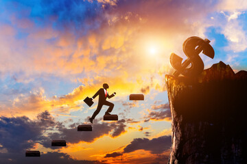 At sunrise, a businessman silhouette walks up the stairs to the dollar sign on the top of the mountain.
