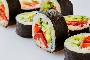 Vegetarian sushi rolls with cucumber, sweet pepper, avocado and lettuce on a white background