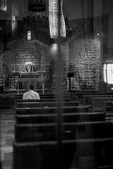 Man praying in a chapel photographed through the glass