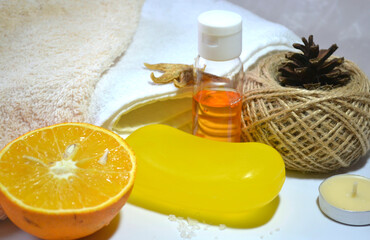 Orange spa composition of handmade dry shampoo, orange soap, citrus shampoo, salt, seashells, candles, organic cotton towels against ecru background. Tonic and vitaminizing products. Organic cosmetics