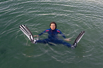 Obraz premium Beach vacation fun woman wearing a wetsuit and flippers making a goofy face while swimming in ocean water