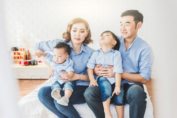 Asian Japanese Family father mother son wearing white shirt carrying child posing for photo on bedroom in white room.To keep memories moment cuteness of son in childhood lifestyle happy