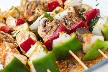 Vegan barbecue skewer. Vegetarian party food with very spiced eggplant, onion and pepper mushrooms. Focus on one point and the rest blurred