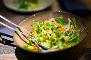Traditional green Chinese cucumber salad with cilantro and cashews on a plate in soft focus