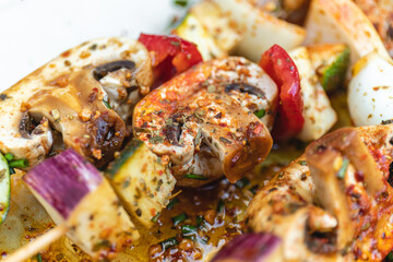 Vegan barbecue skewer. Vegetarian party food with very spiced eggplant, onion and pepper mushrooms. Focus on one point and the rest blurred