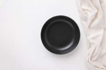 Obraz na płótnie Canvas Black empty plate with a napkin on a white background, top view,copy space.