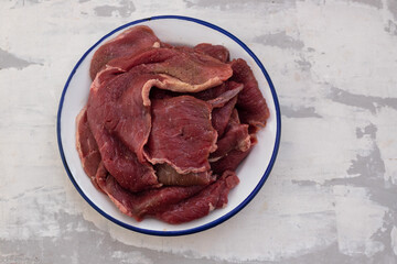 raw meat on white dish on ceramic background