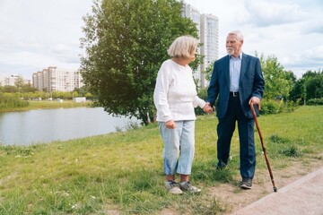 An adult European couple walks around the city. A walk in the fresh air grandparents go by the hand in urban.