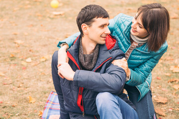 Fototapeta premium Casual family couple of man and woman on a free time in park. Autumn cloudy weather with fallen leafs. Copy space