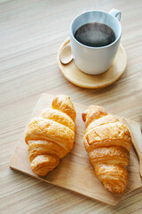 Coffee croissant on wooden background empty.